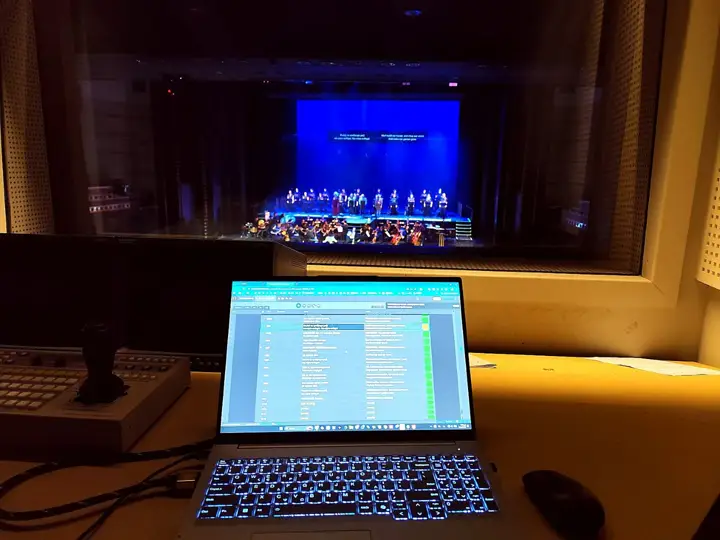 The booth at Megaron, the cue list on a laptop and the stage through the glass.