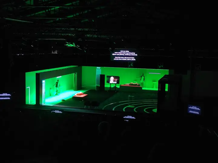 Titles on screens around a stage.